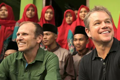 Waterwideweb.org founders Gary White and Matt Damon smiling in front of a group of people.