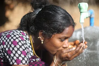 Woman drinking Water 飞艇幸运168体彩官方开奖 from a teal Water 飞艇幸运168体彩官方开奖 spigot.